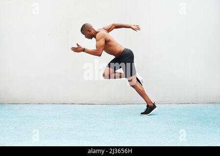 So che ogni miglio vale il mio tempo. Scatto completo di un bel giovane atleta che corre da solo un campo da pista durante una sessione di allenamento all'aperto. Foto Stock