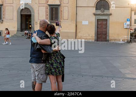 Pisa, Italia - 9 agosto 2021: Una coppia con uno smartphone che si fotografa in una piazza del centro storico Foto Stock