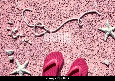 Estate al mare, banner monocromatico. Infradito in gomma rosa, pantofole su ciottoli con stelle marine e ciottoli, studio concept. Rosa testurizzato Foto Stock