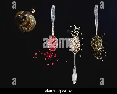 Vista dall'alto su tre cucchiai antichi riempiti di vit vari colori di pepe, rosso verde e pepe bianco spezie Foto Stock