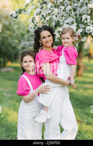 Giovane bella madre è felice con le sue figlie carine nel parco Foto Stock