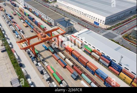 NANTONG, CINA - 6 APRILE 2022 - Foto aerea scattata il 6 aprile 2022 mostra attrezzature pesanti di sollevamento che sollevano container su un treno al Log ferroviario Foto Stock