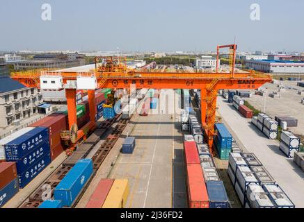 NANTONG, CINA - 6 APRILE 2022 - Foto aerea scattata il 6 aprile 2022 mostra attrezzature pesanti di sollevamento che sollevano container su un treno al Log ferroviario Foto Stock