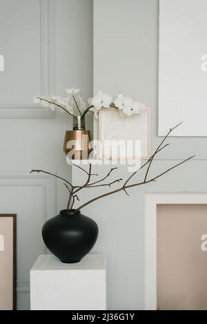Elegante arredamento minimalista scandinavo in grigio. Rami di alberi primaverili in vasi in camera Foto Stock