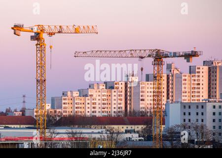 Berlino, Germania. 27th Mar 2022. Le gru da costruzione brillano d'oro alla luce del sole nascente di fronte ad una proprietà immobiliare. Credit: dpa/dpa-Zentralbild/dpa/Alamy Live News Foto Stock