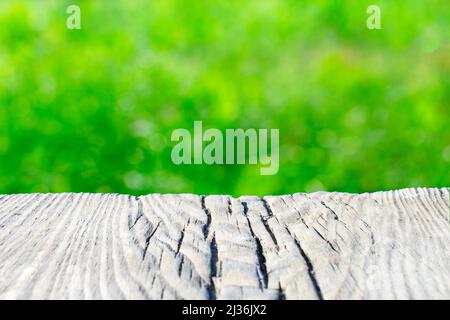 Vecchio asse di legno su uno sfondo sfumato verde frondoso. Luogo per il testo, base per le cartoline. Foto Stock