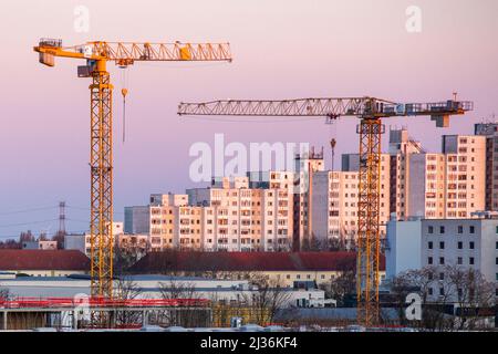 Berlino, Germania. 27th Mar 2022. Le gru da costruzione brillano d'oro alla luce del sole nascente di fronte ad una proprietà immobiliare. Credit: dpa/dpa-Zentralbild/dpa/Alamy Live News Foto Stock