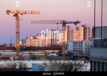 Berlino, Germania. 27th Mar 2022. Le gru da costruzione brillano d'oro alla luce del sole nascente di fronte ad una proprietà immobiliare. Credit: dpa/dpa-Zentralbild/dpa/Alamy Live News Foto Stock