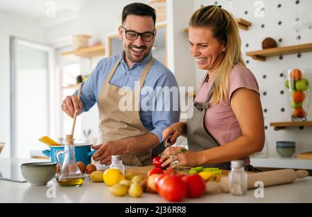 Giovane coppia felice sta godendo e preparando il pasto sano nella loro cucina insieme Foto Stock