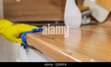 Man pulisce la superficie in legno del piano di lavoro con un panno assorbente Foto Stock