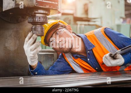 Personale tecnico impostazione lavoro controllo condizione testa di perforazione della macchina CNC per la sicurezza in ambienti di lavoro dell'industria metallurgica. Foto Stock