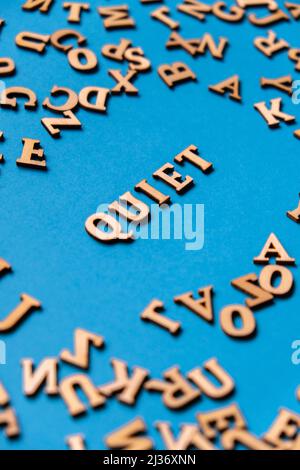 Parola TRANQUILLA fatta di lettere di legno su sfondo blu chiaro. Concetto di citazioni di parole motivazionali. Frase di ispirazione Foto Stock