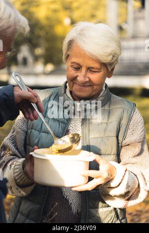 Anziano donna caucasica ottenere cibo da un uomo natura sfondo persone anziane benessere supporto concetto medio shot fuoco selettivo . Foto di alta qualità Foto Stock