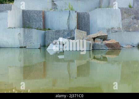 Cava di granito con grandi blocchi di granito abbandonato cava di granito con acqua piovana. Estrazione di granito in una cava. Foto Stock