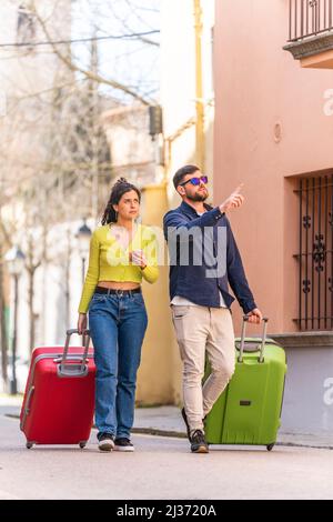 Una coppia di turisti cammina lungo la strada alla ricerca del loro hotel Foto Stock