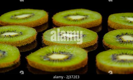 Fette di frutta Kiwi su sfondo nero. Primo piano di kiwi freschi e gustosi, scatto in studio. Foto Stock