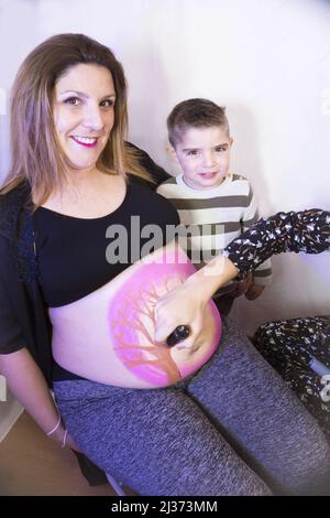 Donna incinta di otto mesi con figlio di tre anni. Verniciatura della carrozzeria Foto Stock