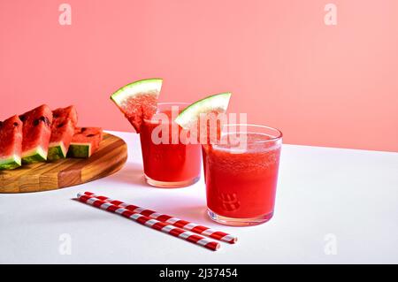 Succo di cocomero fresco o frullato in bicchieri con pezzi di cocomero su sfondo rosa. Rinfrescante drink estivo Foto Stock