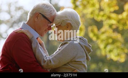 Ritratto di anziano coppia caucasica abbraccio nel parco guardando gli uni gli altri anziani sostegno concetto selettivo fuoco copiare spazio . Foto di alta qualità Foto Stock