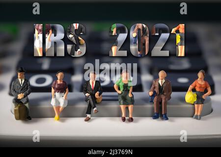 Persone in miniatura: Anziani seduti in una calcolatrice. Reddito e pensioni di sicurezza sociale. IRS 2021 testo Foto Stock