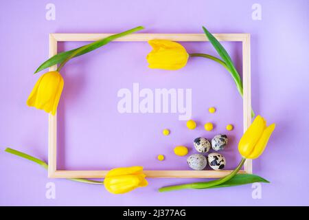 Uova di Pasqua, tulipani e caramelle in una cornice. Vacanza primaverile sfondo. Foto Stock