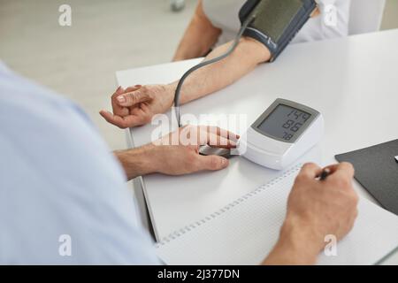 Il medico misura la pressione sanguigna delle donne anziane utilizzando un dispositivo di misurazione digitale elettronico. Foto Stock