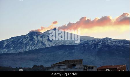 Ammira la vetta invernale dell'Etna fumando al tramonto, in Sicilia Foto Stock