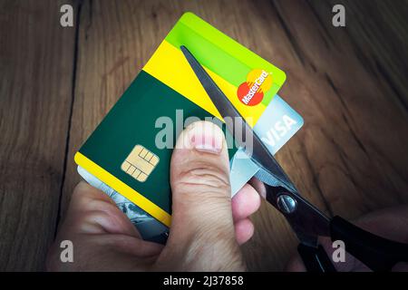 Aprile 2, 2022. Barnaul. Russia: Un uomo taglia le carte di credito bancarie del tipo e mastercard con le forbici. Distruzione delle carte di plastica dopo gli espirati Foto Stock