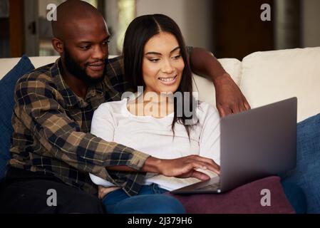 Ha fatto un uomo di me. Scatto di una giovane coppia che passa del tempo di qualità insieme mentre guardi un film su un notebook a casa. Foto Stock