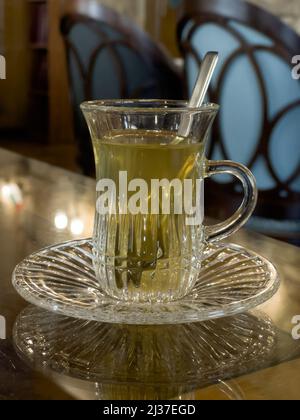 Primo piano di una tazza di tè marocchino servito sul tavolo. Messa a fuoco selettiva sulla tazza. Foto Stock