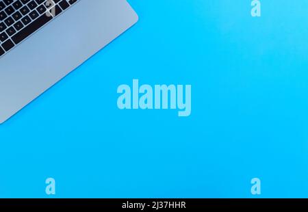 Tavolo da ufficio blu con computer portatile. Vista dall'alto con spazio di copia in layout flay. Concetto di scuola o di lavoro. Foto Stock