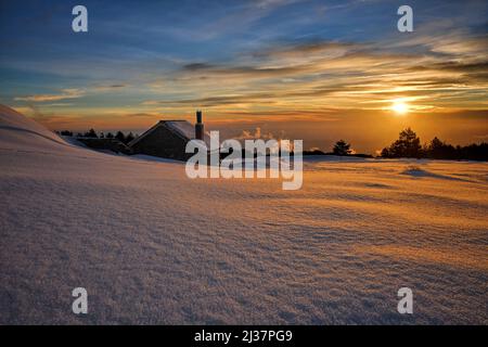 Casa in pietra nella neve al tramonto nel Parco dell'Etna, Sicilia Foto Stock