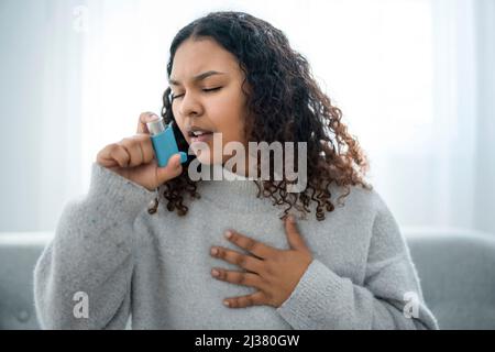 donna nera che prende il suo inalatore a casa nel soggiorno Foto Stock