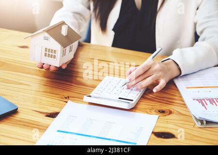 Agenti immobiliari, acquisti e vendite di terreni, tasse di proprietà, proprietari di immobili stanno usando calcolatrici per calcolare le spese di casa e di tasse di terra a. Foto Stock