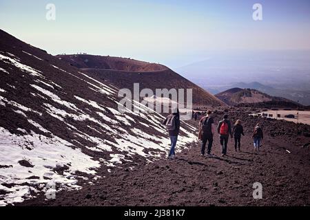 Un gruppo di giovani turisti con un piccolo zaino stanno camminando tra alcune delle centinaia di crateri, più o meno vecchi, nel Parco dell'Etna - Sicilia Foto Stock