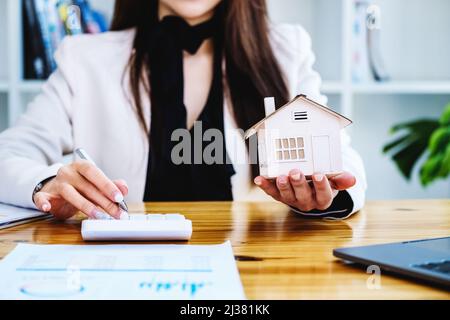 Agenti immobiliari, acquisti e vendite di terreni, tasse di proprietà, proprietari di immobili stanno usando calcolatrici per calcolare le spese di casa e di tasse di terra a. Foto Stock