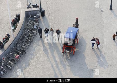 Grote Markt (Piazza del mercato), Bruges vista dall'alto con cavalli e carrozza, persone che camminano, biciclette parcheggiate e sole basso Foto Stock