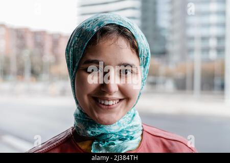 Ragazza musulmana felice sorridendo sulla macchina fotografica all'aperto - fuoco sul volto Foto Stock