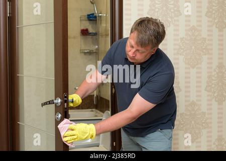 Un uomo biondo adulto lava la porta del bagno. Foto Stock