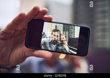 Fare dei ricordi. Ritratto di due giovani e allegri colleghi di lavoro che prendono un ritratto insieme fuori durante il giorno. Foto Stock