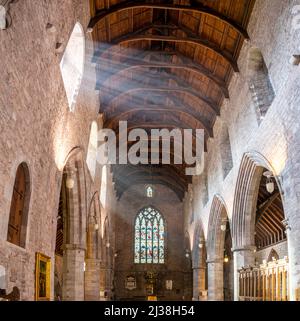 Le travi di luce del mattino passano attraverso le finestre laterali, travi in legno e travi formano il soffitto della Cattedrale, archi, pareti in mattoni e vetrate colorate. Foto Stock