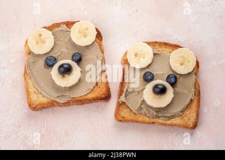 I bambini allegri sopportano toast con i butters di noci per la prima colazione Foto Stock