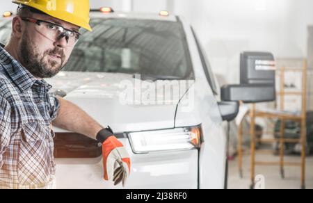 Giovane costruttore caucasico nel suo 30s indossare occhiali di protezione per gli occhi e un cappello rigido. Stare accanto al suo moderno camion Heavy Duty Pickup. Foto Stock