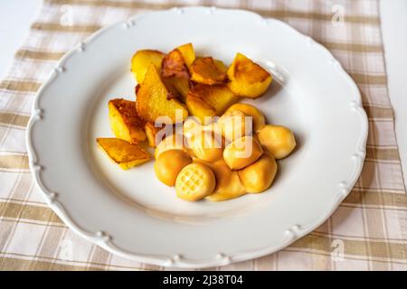 Polpette di formaggio affumicate con patate fritte sul piatto, primo piano. Foto Stock