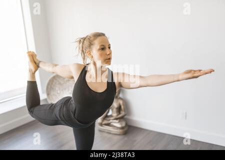 Giovane donna sportiva che pratica lo yoga e che ha un equilibrio naturale Foto Stock