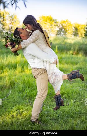 lo sposo tiene la sposa tra le braccia Foto Stock