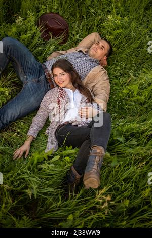 Giovane coppia che ha pic-nic nel prato in giorno di sole luminoso. L'uomo e la donna si godono l'un l'altro Company.A coppia in amore si trova su un prato verde. Foto Stock