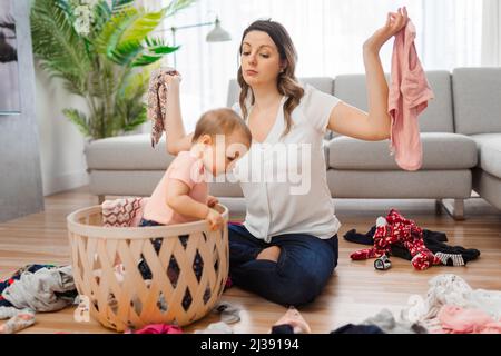 la donna ha problemi a scegliere i vestiti con il bambino nel soggiorno Foto Stock