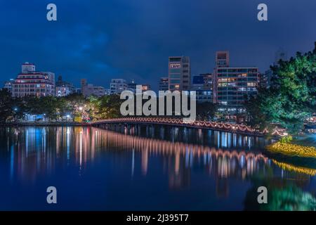 fukuoka, kyushu - dicembre 06 2021: Vista notturna del ponte di Kangetsu illuminarsi con le ghirlande luminose che si riflettono nello stagno del Parco di Ohori con il Th Foto Stock