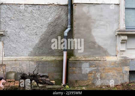 Danni all'acqua di una casa. Parete esterna bagnata a causa di una perdita in un tubo del gocciolatoio del tetto. L'acqua piovana viene assorbita dall'edificio. Costi elevati Foto Stock